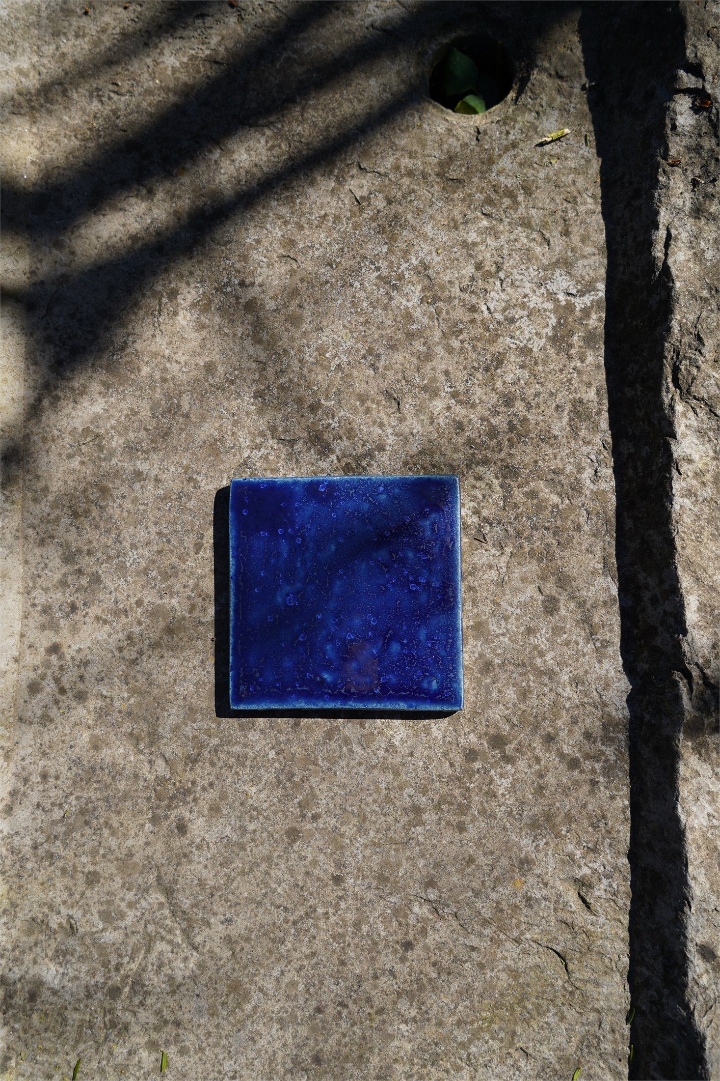 Single cobalt handmade tile shown against Belgian stone.