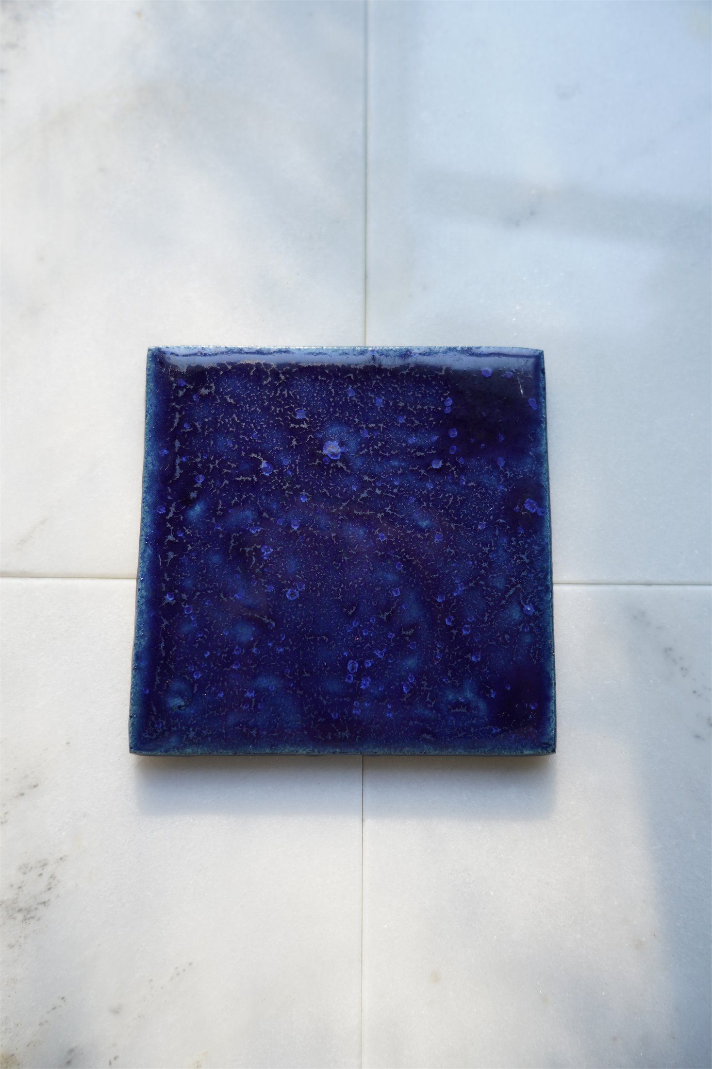 Cobalt glaze on handmade ceramic tile, photographed on Carrara marble.