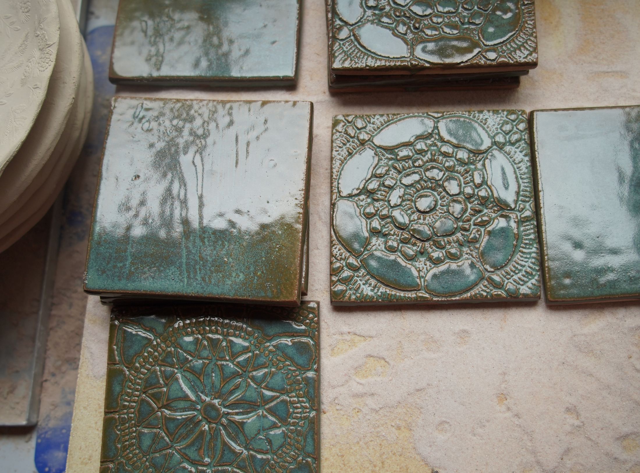 Editorial study of verdigris handmade ceramic tiles with relief and glaze variation.