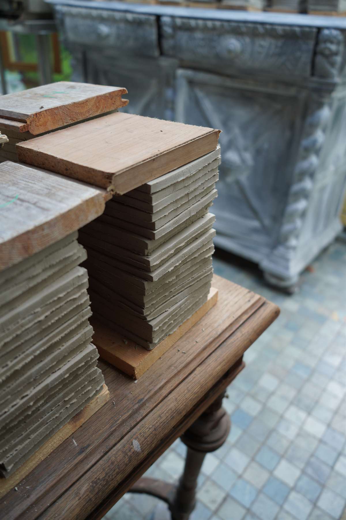 Raw tiles drying between wood in the atelier.