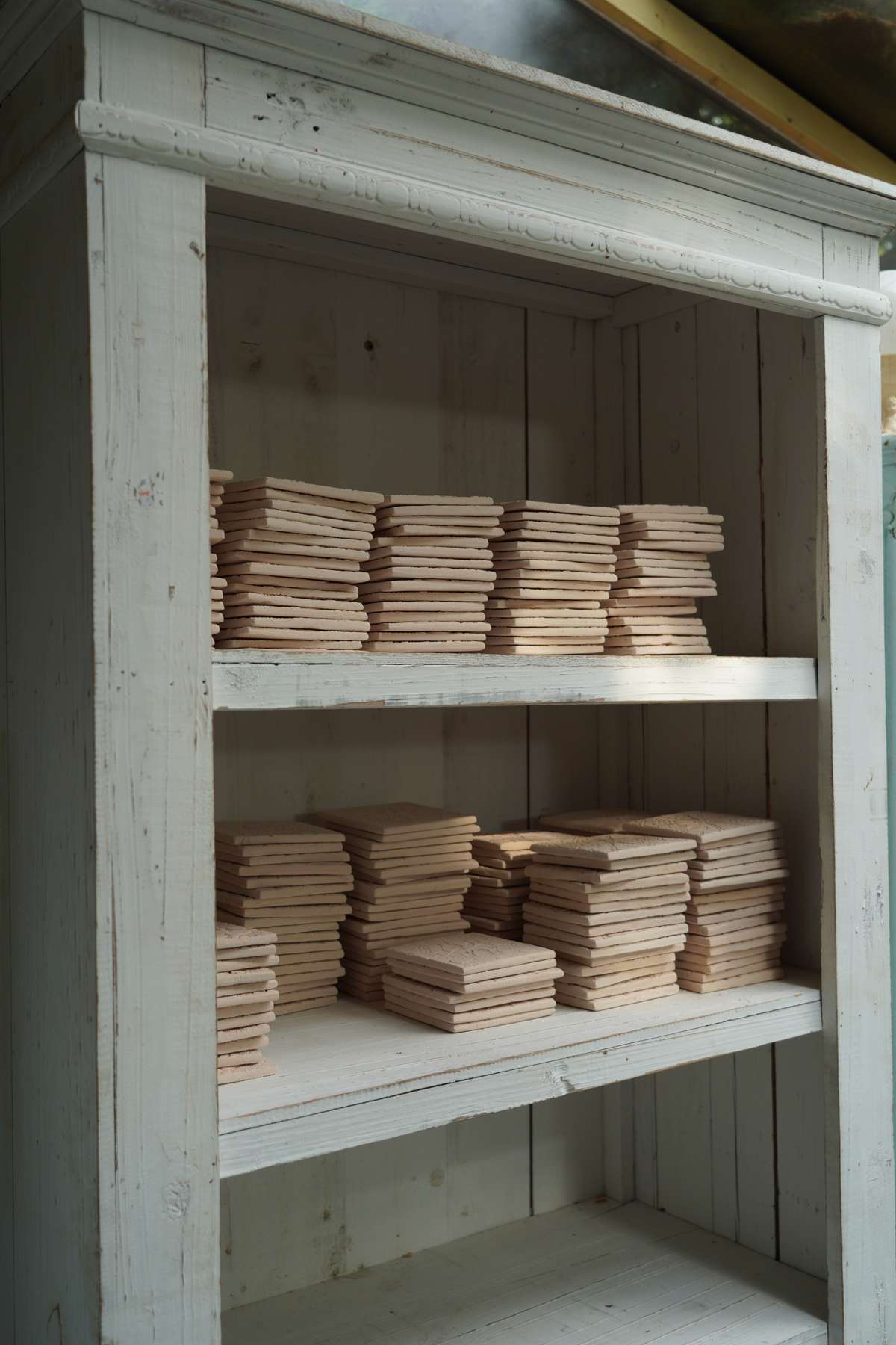 Prepared raw tiles stacked between drying boards.