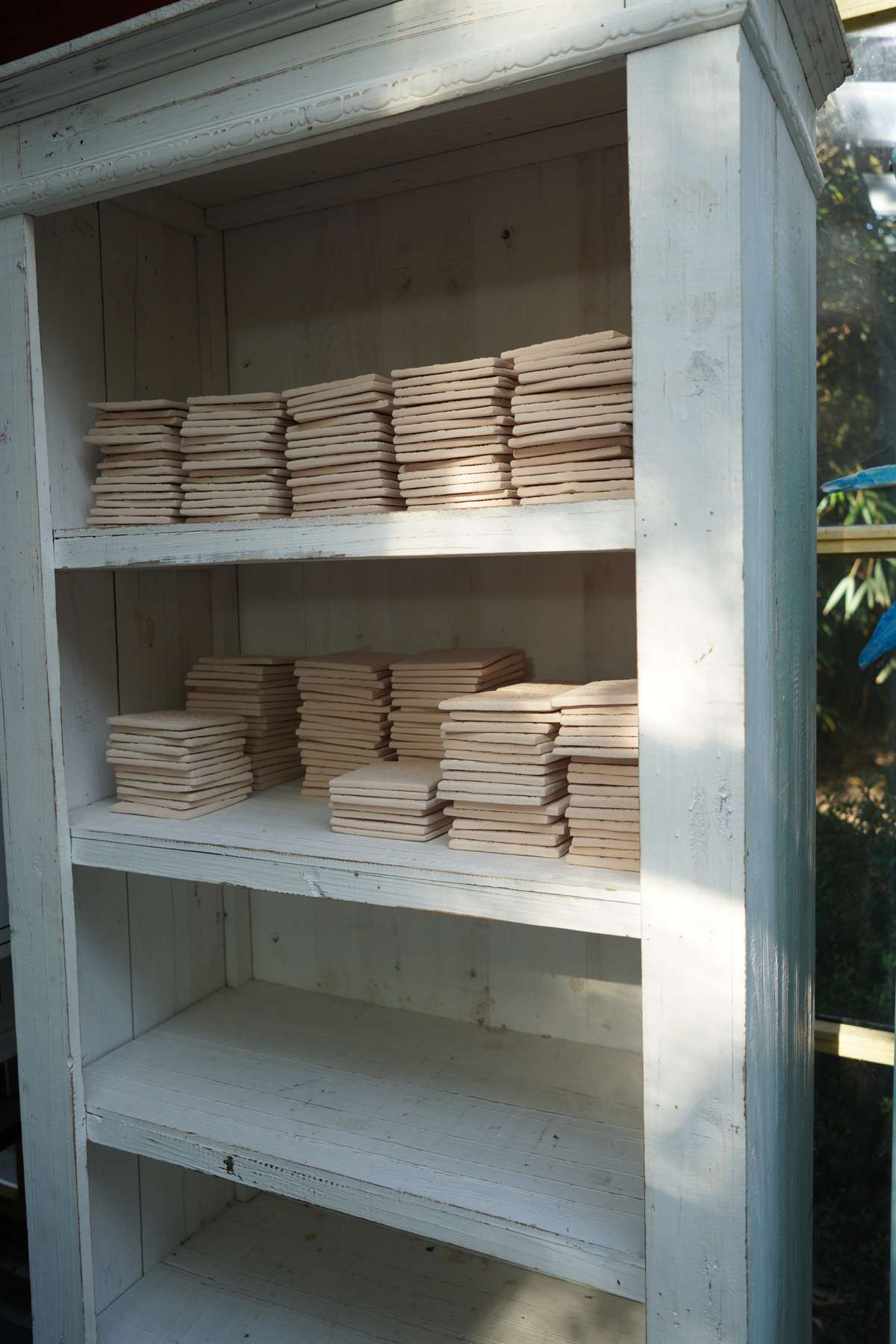 Raw tile stacks drying on open shelving.