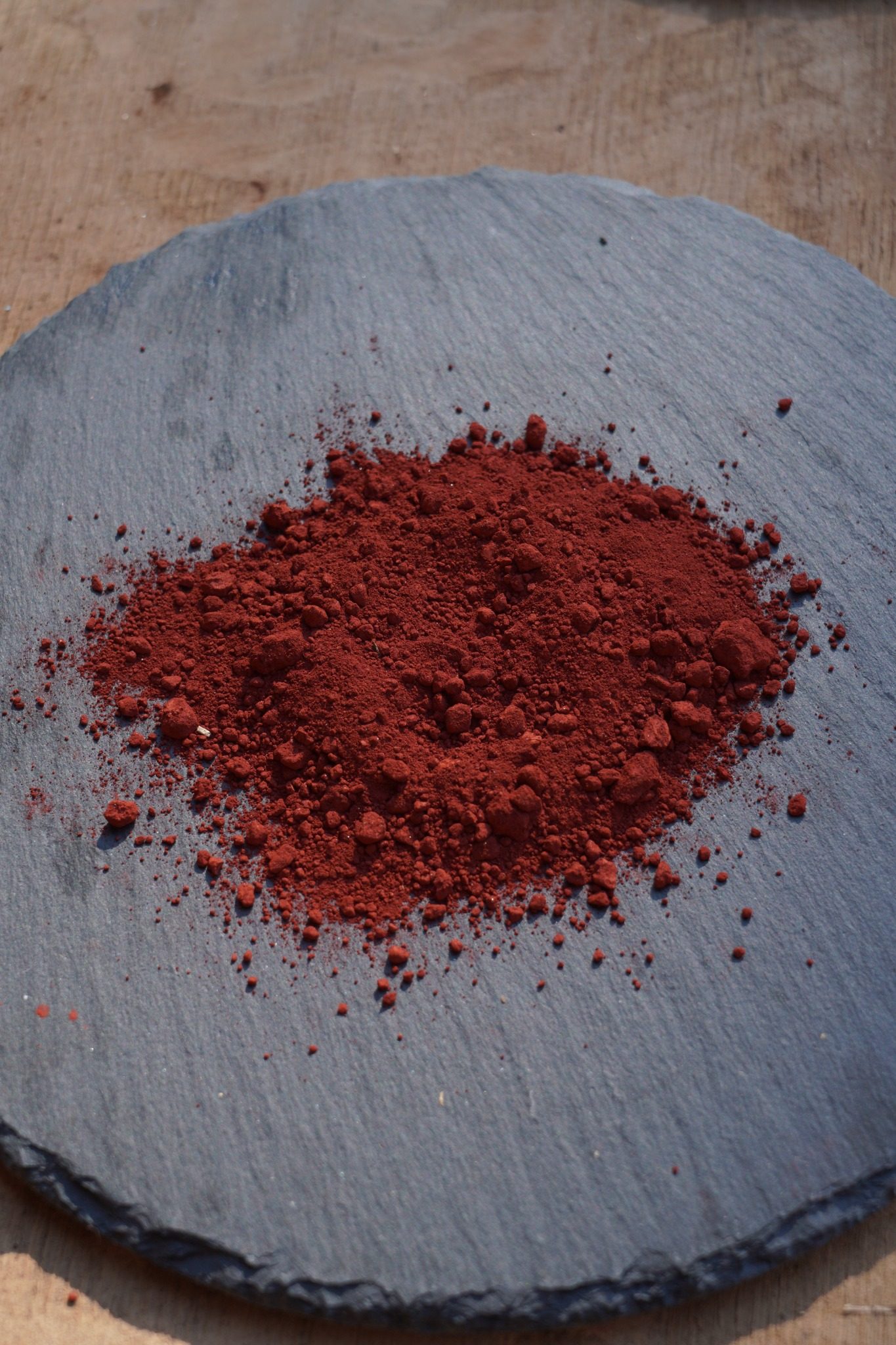Red ceramic pigment resting on a slate surface.