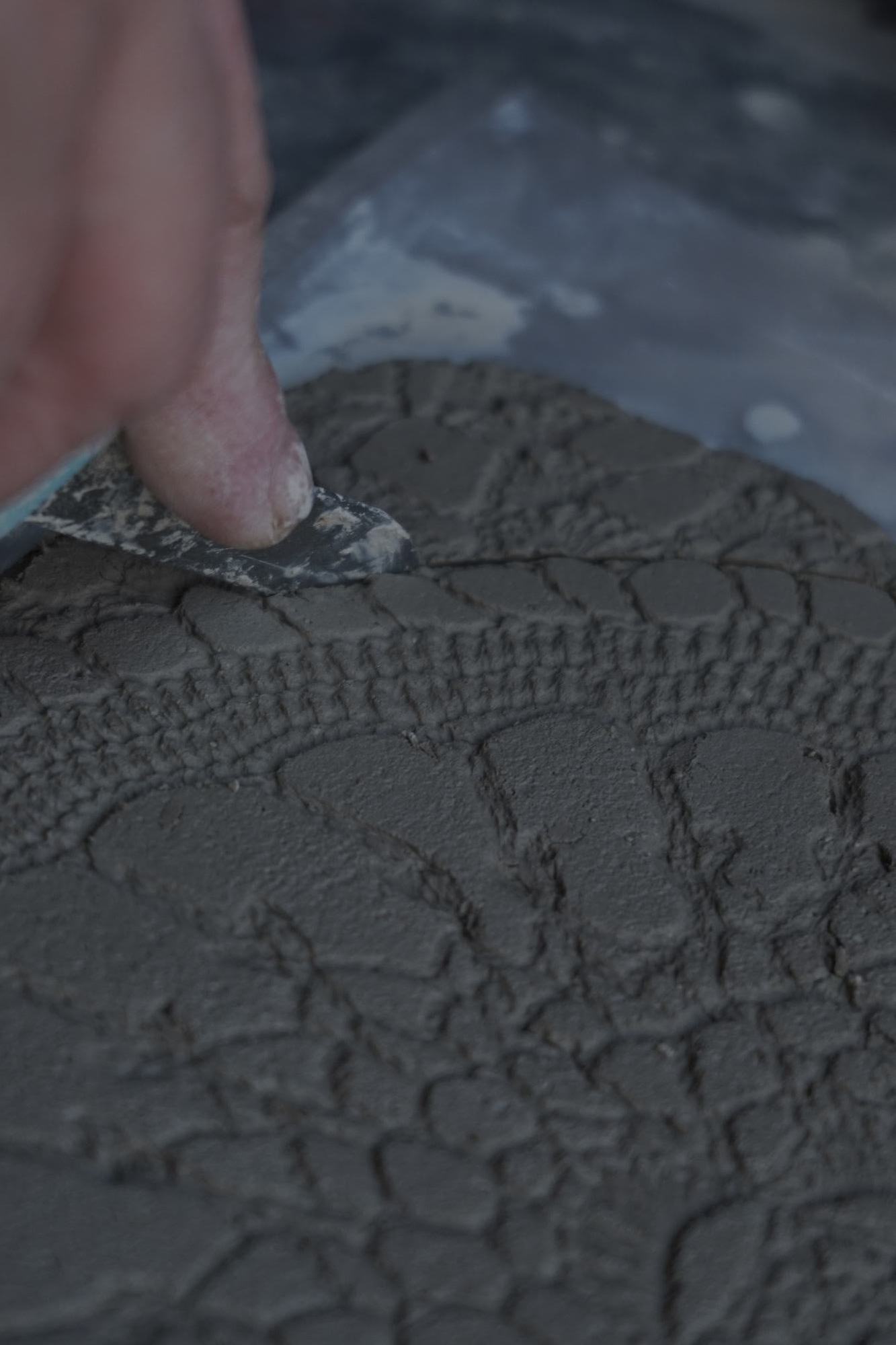 Relief detail being cleaned by hand in wet clay.