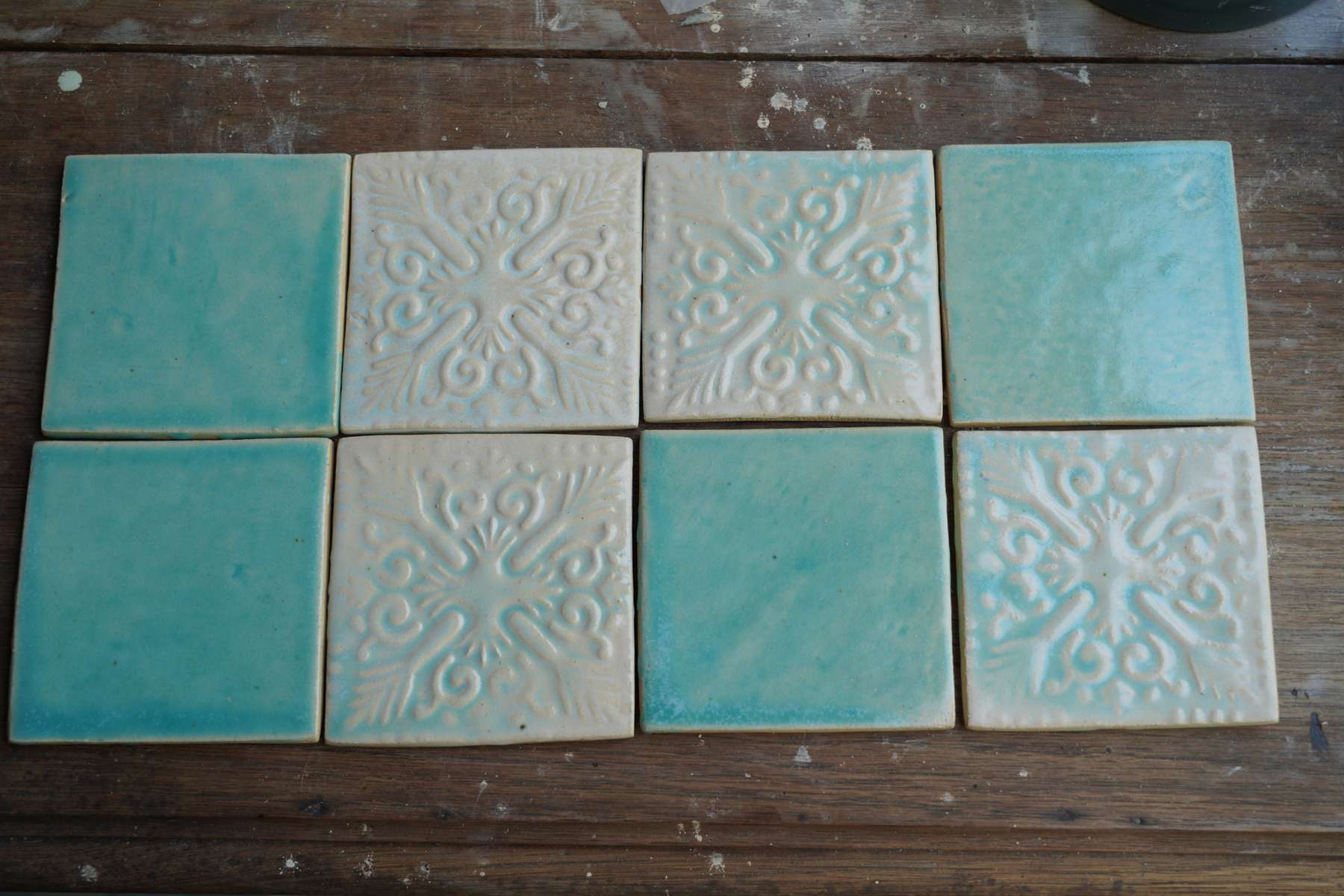 Aqua relief and plain tiles arranged as a surface study.