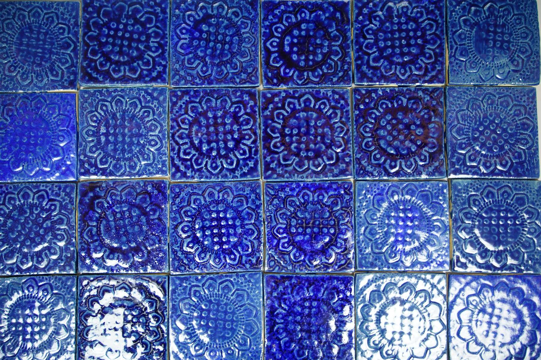Blue relief tile grid with pooled glaze in the recessed pattern.
