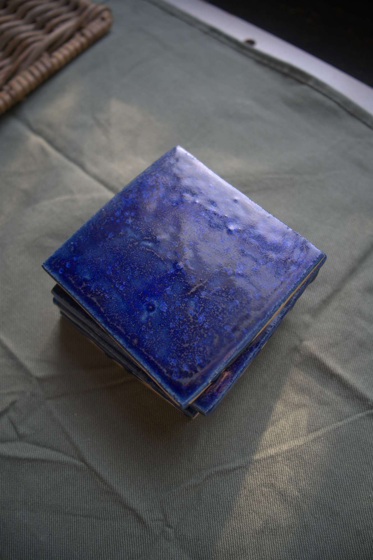 Stack of deep blue handmade tiles on atelier cloth.
