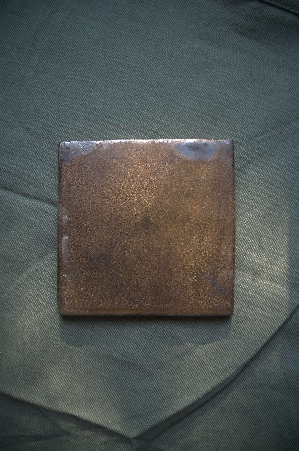 Single mineral bronze tile with subtle metallic movement.