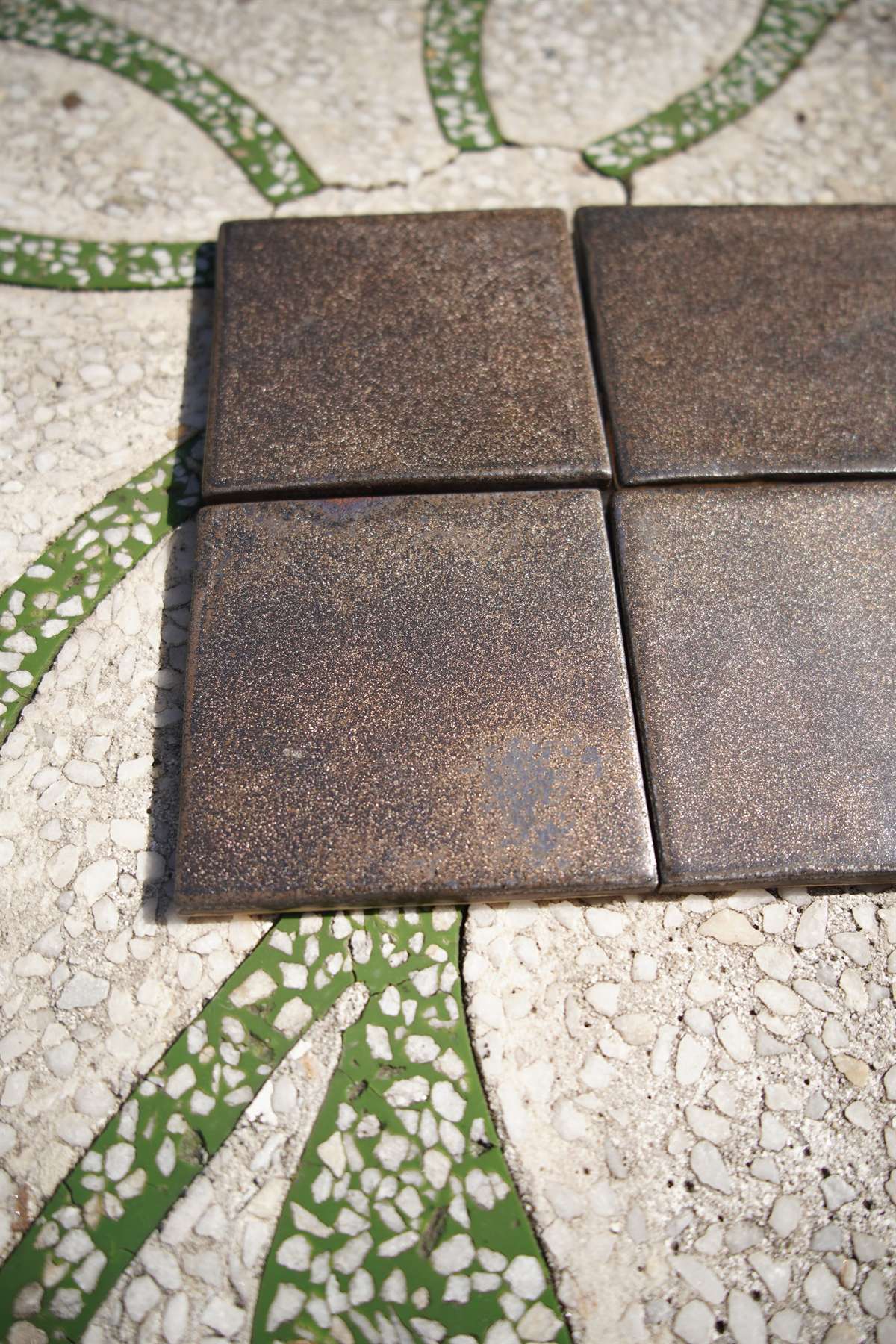 Four bronze-toned handmade ceramic tiles arranged together.
